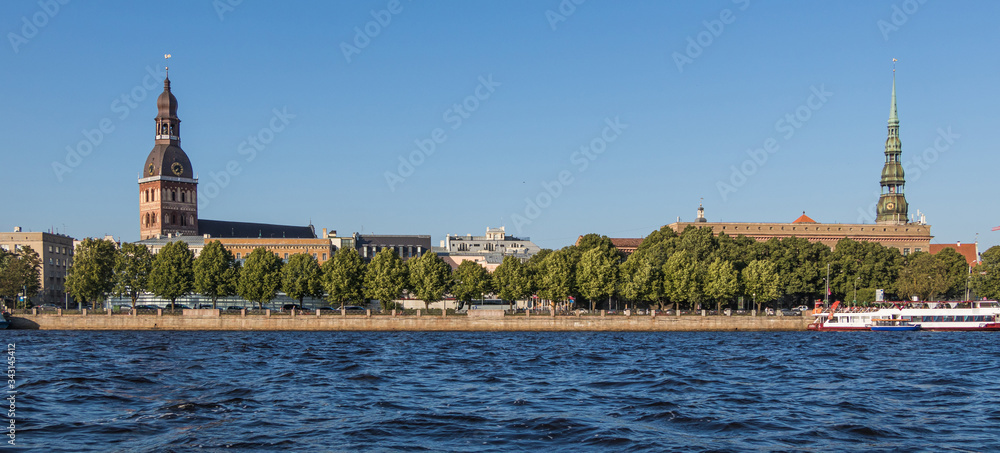 Fototapeta premium Sightseeings of Riga from the river Daugava. View of the Dome Cathedral, St. Peter's Church and the promenade.