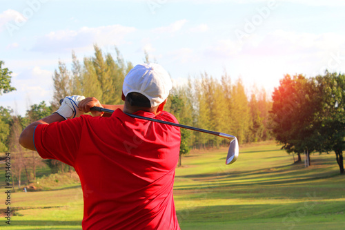 Athletes who are doing work of golf competition. Meaning that he is hitting the lace 1 as close as possible On the golf course background and the light from the sun shining
