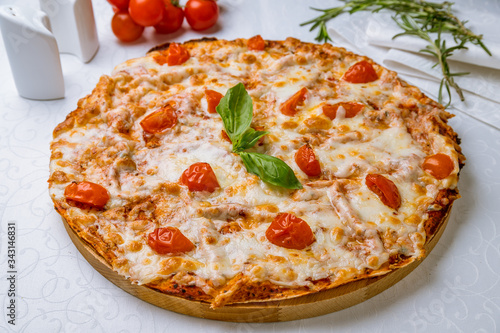Italian pizza Margherita with tomatoes and basil on white table