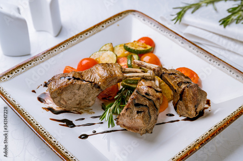 Rack of lamb with fried vegetables on white table
