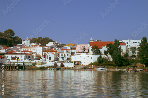 Wallpaper Mural Alcoutim, un pequeño pueblo de la región del Algarve en Portugal. Vista de su puerto deportivo y casas a orillas del río Guadiana desde la orilla española en Sanlúcar de Guadiana. Torontodigital.ca