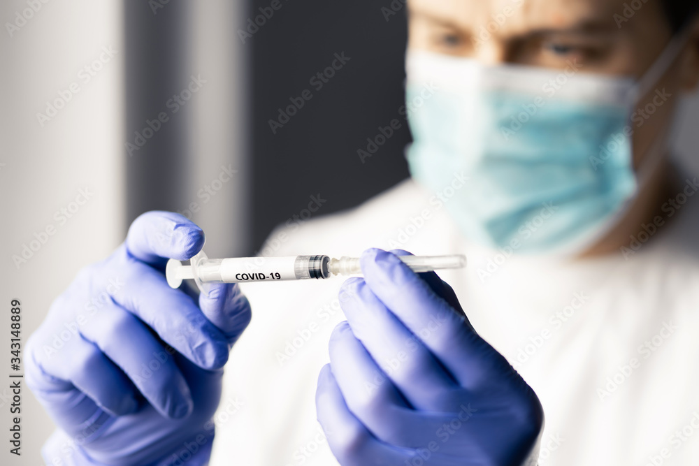 Doctor or nurse looking at a syringe needle for coronavirus vaccine. Medical professional or scientist working in lab for research, immunity and cure for covid 19. Person wearing mask and gloves. Doctor or nurse looking at a syringe needle for coronavirus vaccine. Medical professional or scientist working in lab for research, immunity and cure for covid 19. Person wearing mask and gloves.
