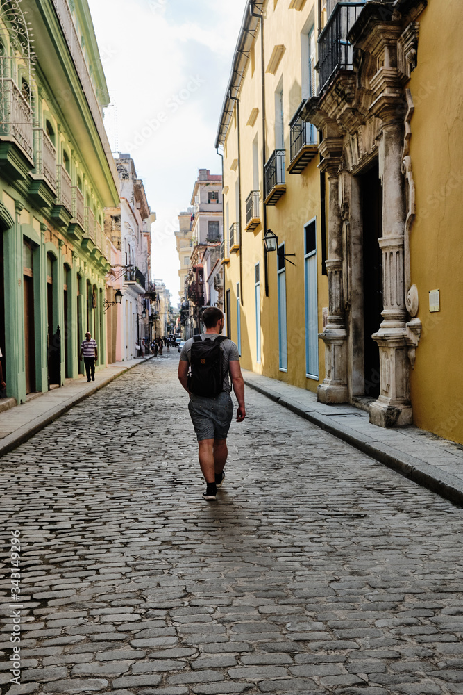 Man with a backpack on walking away from the camera in Old Havana.