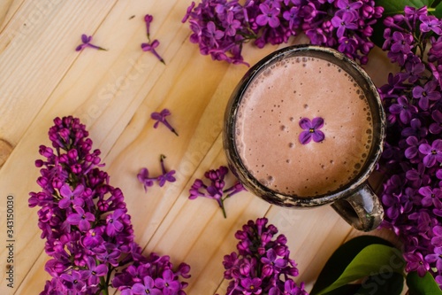 bouquet of lilac flowers and a cup of cocoa on the table