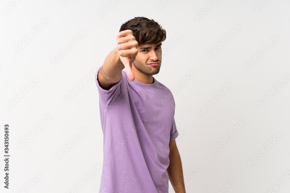 Young handsome man over isolated white background showing thumb down with negative expression Young handsome man over isolated white background showing thumb down with negative expression