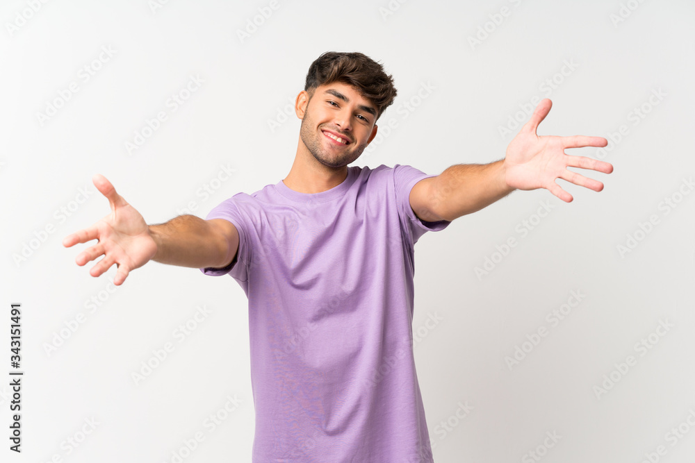 Young handsome man over isolated white background presenting and inviting to come with hand Young handsome man over isolated white background presenting and inviting to come with hand