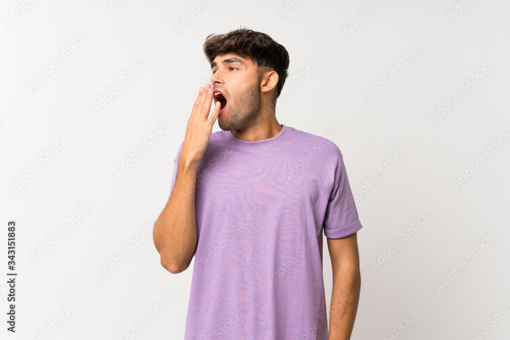 Young handsome man over isolated white background yawning and covering wide open mouth with hand Young handsome man over isolated white background yawning and covering wide open mouth with hand