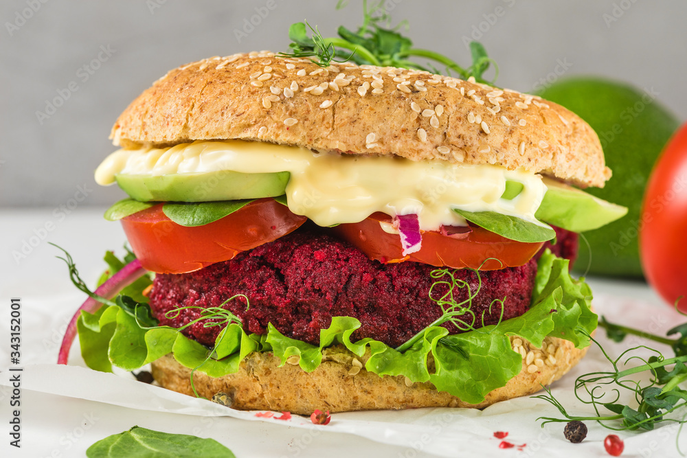 Vegan beetroot burger with avocado, salad, tomato, sprouts and vegan mayonnaise on white marble table Vegan beetroot burger with avocado, salad, tomato, sprouts and vegan mayonnaise on white marble table