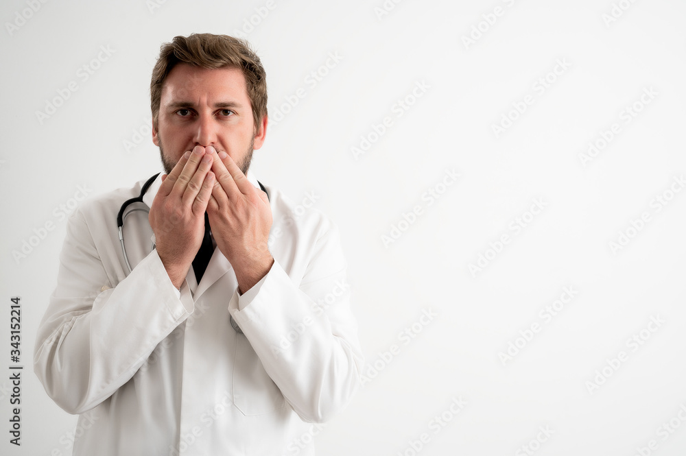 Male doctor with stethoscope in medical uniform covering mouth like mute concept Male doctor with stethoscope in medical uniform covering mouth like mute concept
