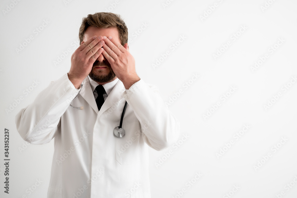 Male doctor with stethoscope in medical uniform covering eye like blind concept Male doctor with stethoscope in medical uniform covering eye like blind concept