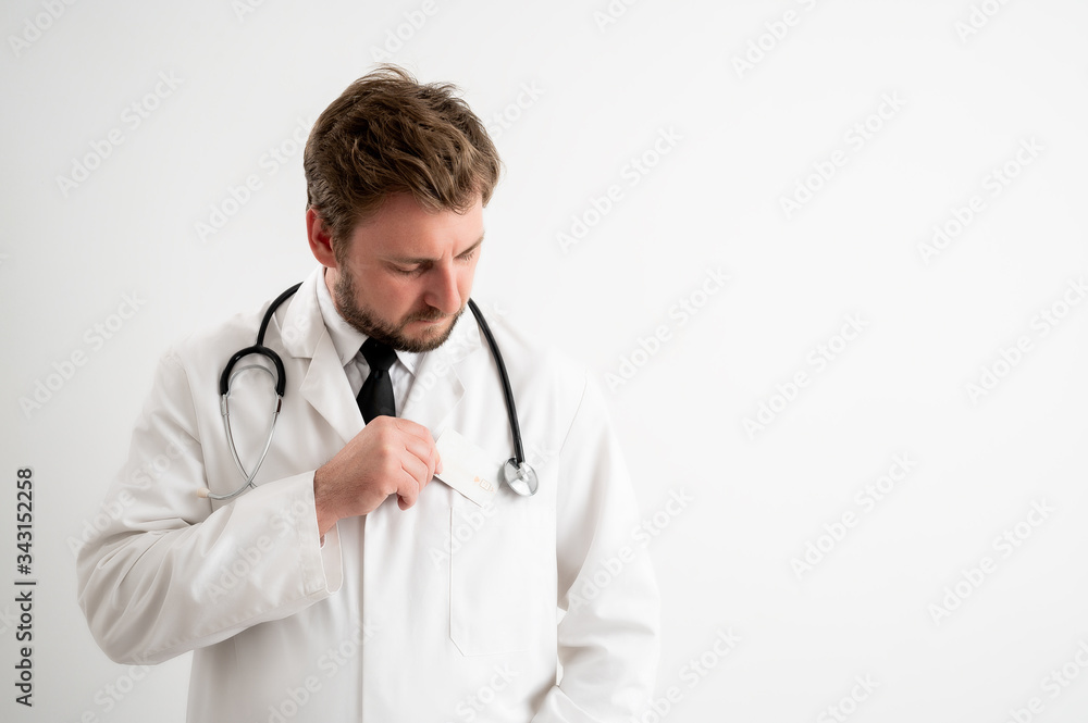Male doctor with stethoscope in medical uniform pull out card from her pocket Male doctor with stethoscope in medical uniform pull out card from her pocket