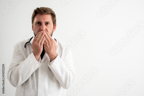 Male doctor with stethoscope in medical uniform covering mouth like mute concept
