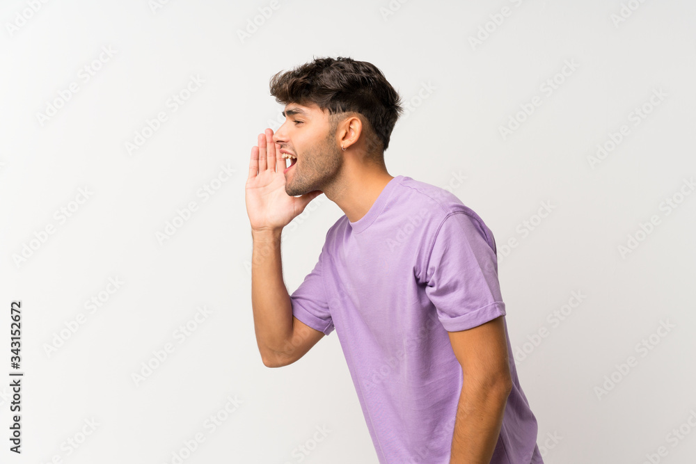 Young handsome man over isolated white background shouting with mouth wide open to the lateral Young handsome man over isolated white background shouting with mouth wide open to the lateral