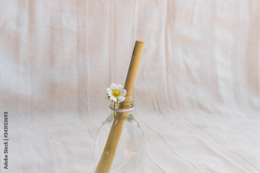 Eco Bamboo Straw on a refreshing soft summer drink with flowers. Eco friendly and natural concept. Crystal bottle. Eco Bamboo Straw on a refreshing soft summer drink with flowers. Eco friendly and natural concept. Crystal bottle.