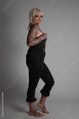 Tattooed Model. Young blonde woman with many tattoos wearing a body siut. Posing on a white background.
