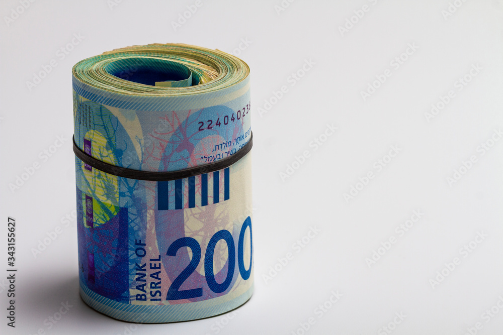 The money of the new Israeli shekel. Banknotes of 200 twisted roll stand on a light background. The money of the new Israeli shekel. Banknotes of 200 twisted roll stand on a light background.