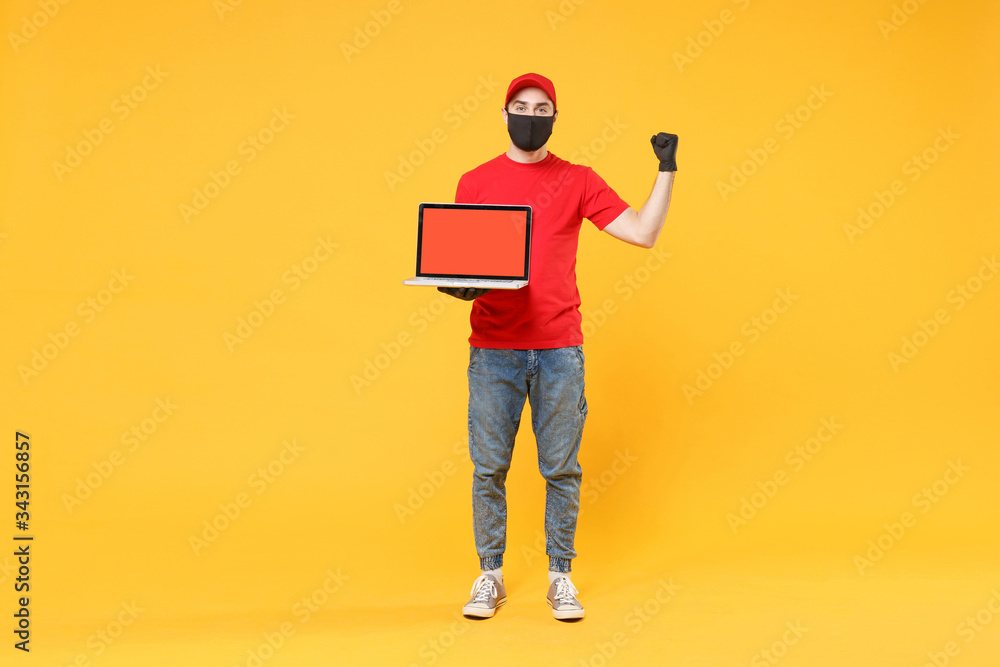 Delivery man in red cap blank t-shirt uniform mask gloves isolated on yellow background studio Guy employee work hold laptop pc computer Service quarantine pandemic coronavirus virus 2019-ncov concept Delivery man in red cap blank t-shirt uniform mask gloves isolated on yellow background studio Guy employee work hold laptop pc computer Service quarantine pandemic coronavirus virus 2019-ncov concept
