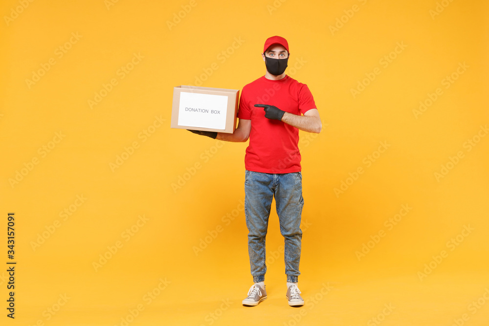 Delivery man employee in red cap blank t-shirt uniform face mask glove hold donations cardboard box isolated on yellow background studio Service quarantine pandemic coronavirus virus 2019-ncov concept Delivery man employee in red cap blank t-shirt uniform face mask glove hold donations cardboard box isolated on yellow background studio Service quarantine pandemic coronavirus virus 2019-ncov concept