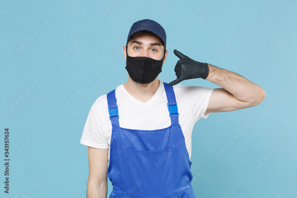 Delivery man in cap t-shirt coveralls uniform sterile face mask gloves isolated on blue background studio. Guy employee courier Service quarantine pandemic coronavirus virus covid-19 2019-ncov concept Delivery man in cap t-shirt coveralls uniform sterile face mask gloves isolated on blue background studio. Guy employee courier Service quarantine pandemic coronavirus virus covid-19 2019-ncov concept