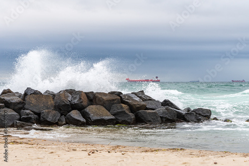 Cargo ships waiting for orders with boulders in foreground near Skagen, Denmark