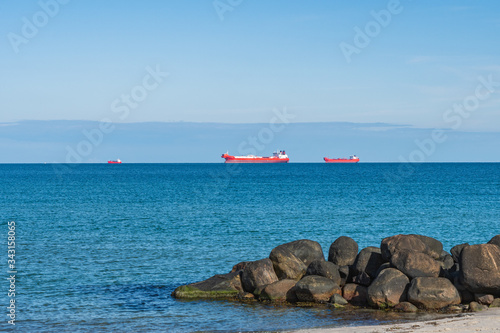 Cargo ships waiting for orders with boulders in foreground near Skagen, Denmark