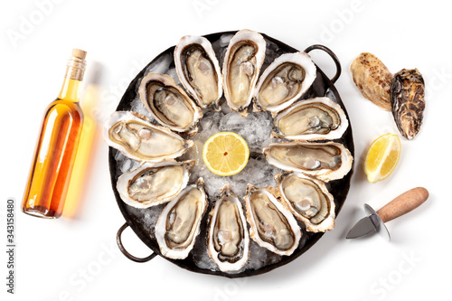 Fototapeta Naklejka Na Ścianę i Meble -  A dozen of oysters with wine and lemons, shot from above on a white background, a flat lay