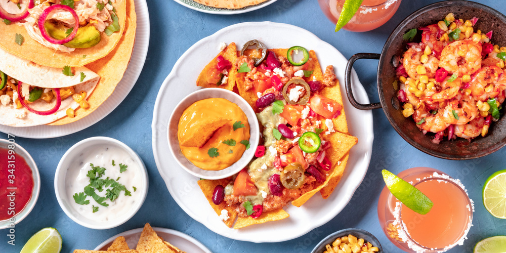 Mexican food panorama, a flat lay. Nachos, tortillas, Paloma cocktails and other dishes, shot from above Mexican food panorama, a flat lay. Nachos, tortillas, Paloma cocktails and other dishes, shot from above
