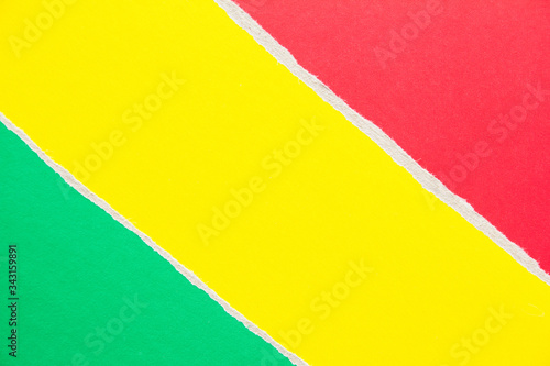Yellow, green and red torn sheet of cardboard paper with diagonal border texture background. Copy space for text message.