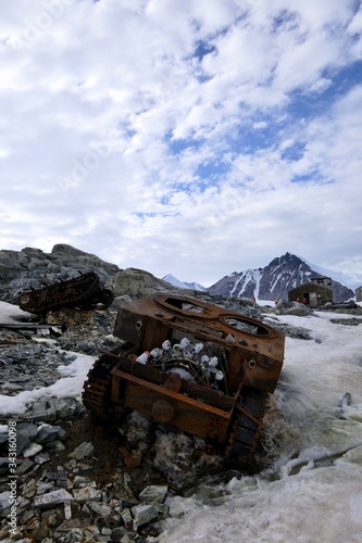 Rusty tank wreck in Antarctica, at Stonington Island, with east base, mountain and explorers in background © HWL Photos