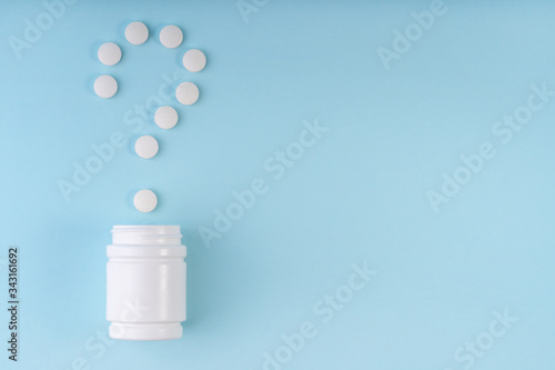 Question sign, mark from pharmaceutical medicine pills. Creative layout of tablets and bottle on blue. Question symbol. Medicine FAQ, healthcare concept. Choice metaphor. Copy space, flat lay
