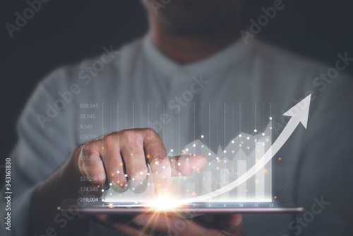 Businessman with a tablet in his hand And touching on the screen That shows a business graph. The concept of starting a new business that goes better.