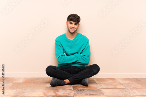Young handsome man sitting on the floor laughing
