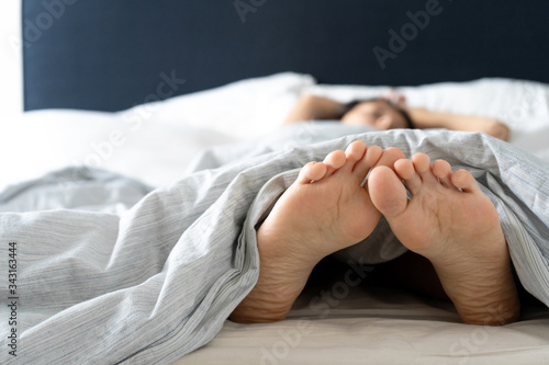 Feet of a sleeping girl in bed in the morning. Spy photo.