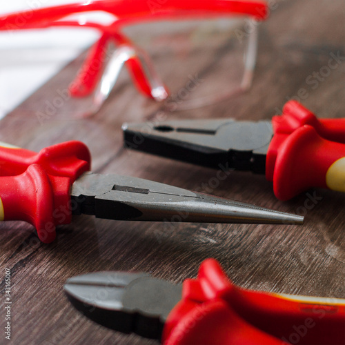 Diferentes herramientras de trabajo color rojo con gafas protectoras sobre un fondo de madera y blaco photo