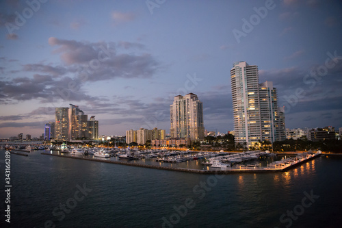 Urban paradise. City skyline. City and yacht club from sea. City architecture at dusk. Twilight of city. Illuminating lights on cloudy evening sky. Travelling and wanderlust. Travel destination © be free
