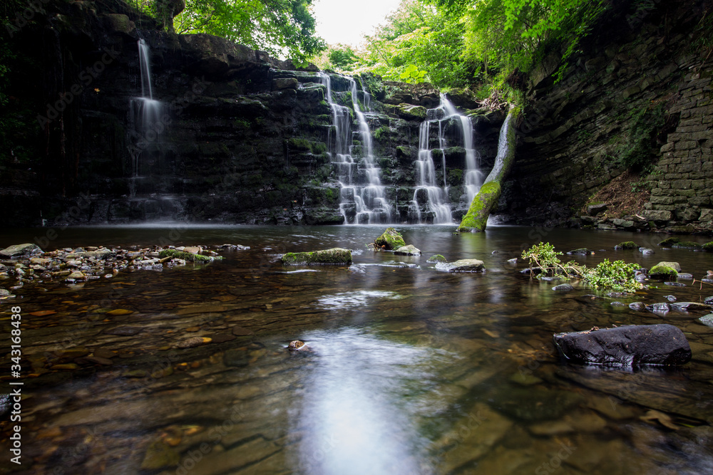 Obraz premium Hidden gorge with a large waterfall with smooth flowing water