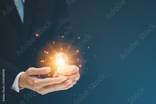 Businessman hold the light bulb in graph Screen Icon of media screen,Technology Process System Business concept.