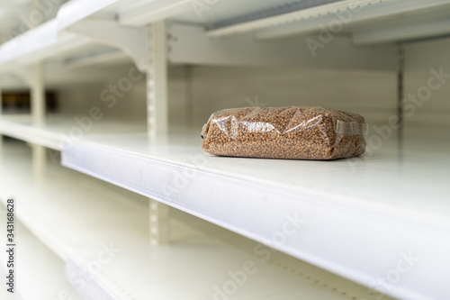 Shopping during virus outbreak. One packet of buckwheat on empty supermarket shelves. grocery store. pandemic. coronavirus. The concept of crisis and food shortages photo