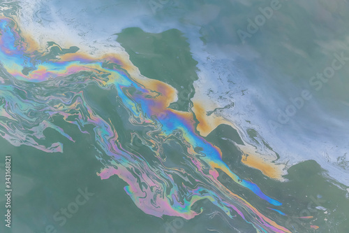 trail of oil on water in ocean creating a colourful trail
