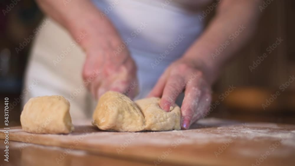 Close up hands cut shape in rolling-pin dough into pieces on wooden board covered with flour Close up hands cut shape in rolling-pin dough into pieces on wooden board covered with flour
