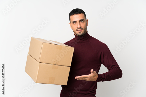 Young man over isolated white background holding a box to move it to another site