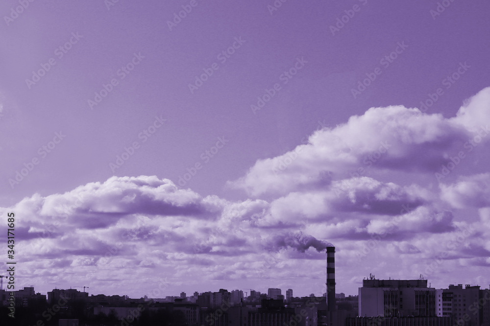 A factory chimney emits clouds of smoke that are mixed with ordinary clouds. The theme of ecology and nature.