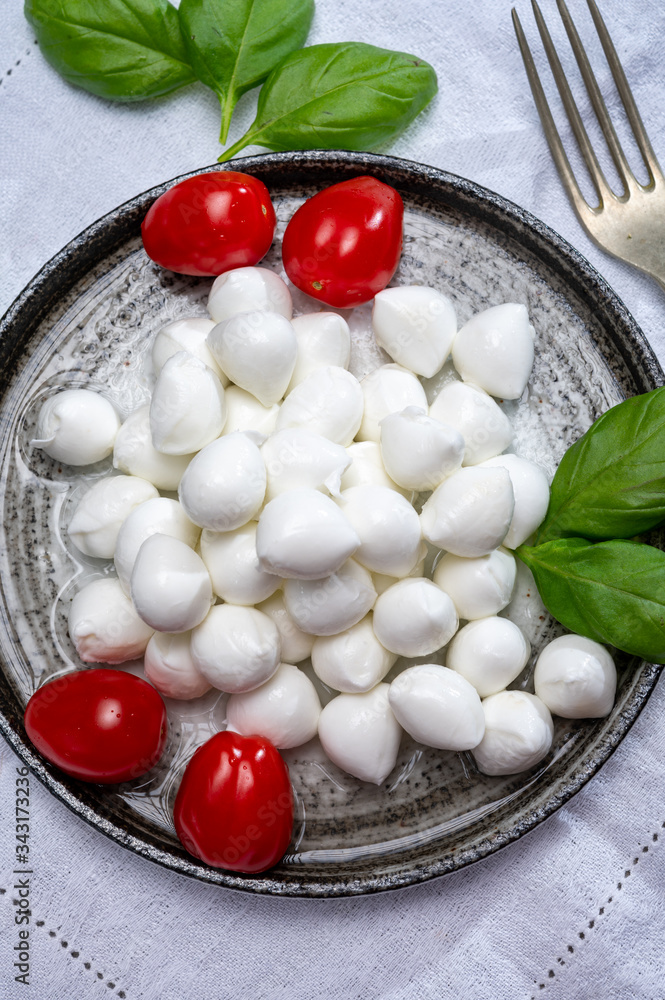 Italian food, fresh fresh green basil, white mini mozzarella cheese and red cherry tomatoes Italian food, fresh fresh green basil, white mini mozzarella cheese and red cherry tomatoes