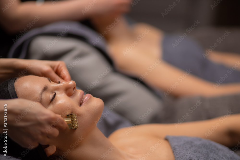 beautiful caucasian healthy women relaxing on massage table, body care in spa salon, massage on face, head, neck, shoulders