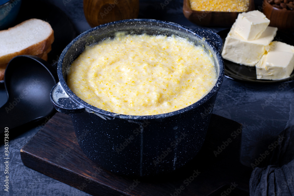 Corn porridge with milk in a black saucepan against the dark background Corn porridge with milk in a black saucepan against the dark background