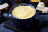Corn porridge with milk in a black saucepan against the dark background