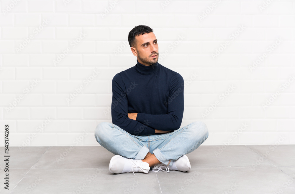 Young handsome man sitting on the floor looking side Young handsome man sitting on the floor looking side