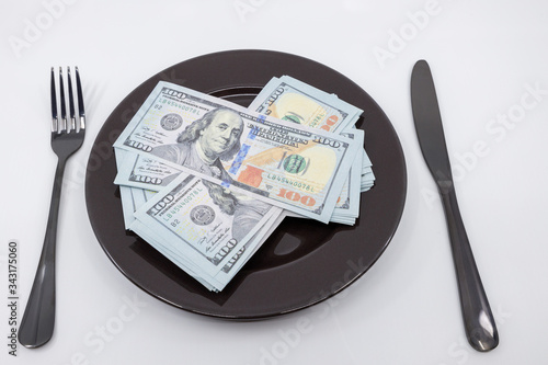 Plate full hundreds of dollar bills with fork and knife. Concept of prosperity and abundance. Full plate concept. Copy space