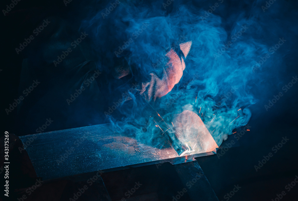 Welding steel structures and bright sparks in steel construction industry. Blue tone - obrazy, fototapety, plakaty 