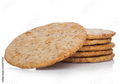 Stack of round organic crispy wheat flatbread salty crackers on white.